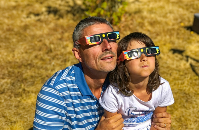 father and daughter watching eclipse with eclipse glasses