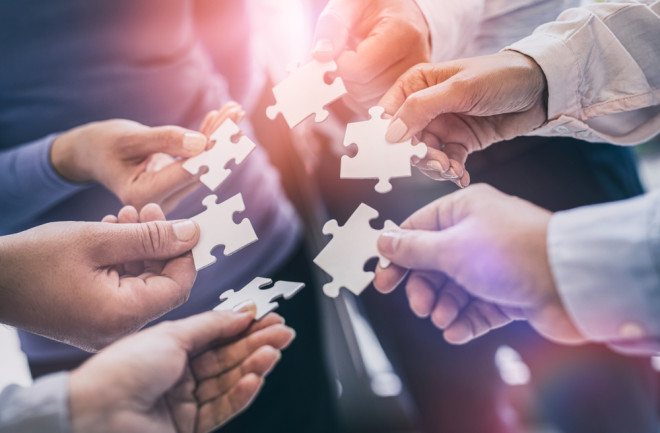 A group of business people assembling jigsaw puzzle. The concept of cooperation, teamwork, help and support in business.