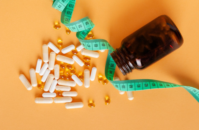 Weight Loss Pills Scattered from Bottle on Yellow Background